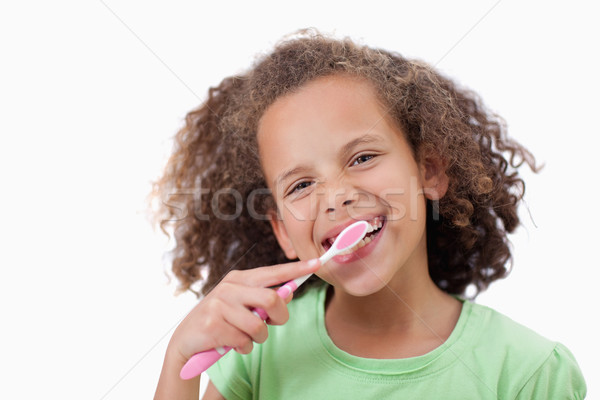 Smiling girl brushing her teeth against a white background Stock photo © wavebreak_media