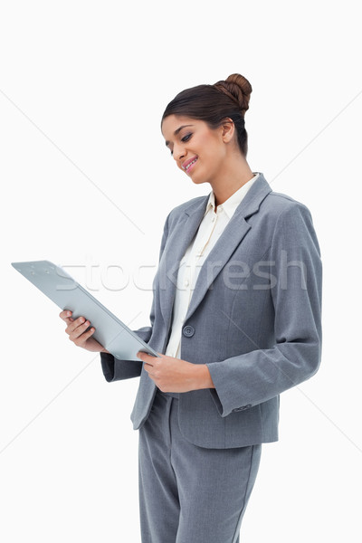 Smiling businesswoman looking at clipboard against a white background Stock photo © wavebreak_media