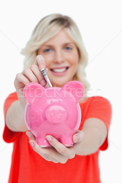 Piggy bank getting dollar notes from a young woman against a white background Stock photo © wavebreak_media