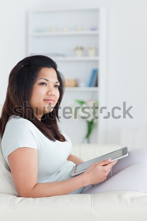 Woman sitting on a couch while holding a tactile tablet in living room Stock photo © wavebreak_media