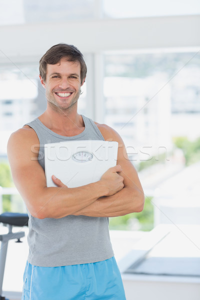 Fit man standing with scale in bright exercise room Stock photo © wavebreak_media