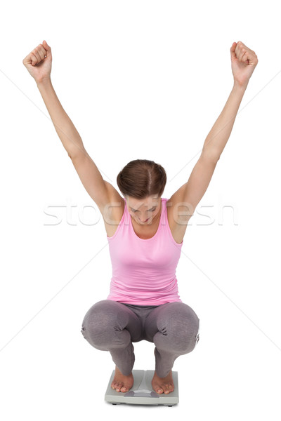 Full length of a young woman cheering on weight scale Stock photo © wavebreak_media