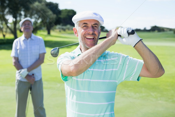 Golfer swinging his club with friend behind him Stock photo © wavebreak_media
