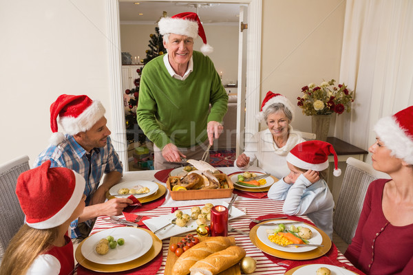 Stock photo: Grandfather in santa hat carving roast turkey at christmas