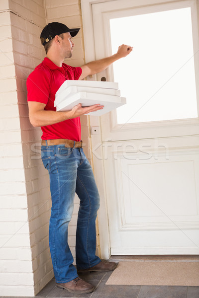 Delivery man holding pizza while knocking on the door Stock photo © wavebreak_media