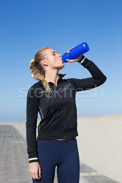 Stock photo: Fit blonde drinking water on the pier