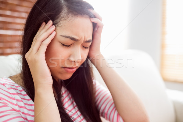 Stock photo: Asian woman getting headache on couch