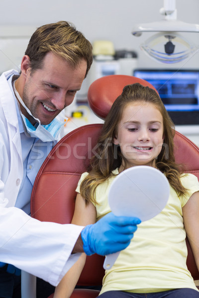 Stock photo: Dentist showing mirror to young patient in dental clinic