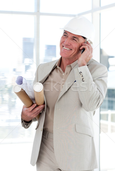 Stock photo: Senior architect on phone carrying blueprints