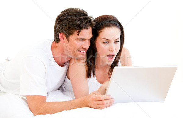 Surprised couple using a computer lying on their bed at home Stock photo © wavebreak_media