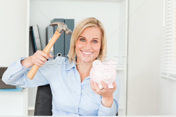 Expectantly woman wanting to destroy her piggy bank in her office Stock photo © wavebreak_media