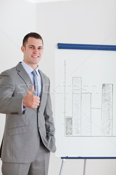 Smiling businessman giving thumb up next to column graph Stock photo © wavebreak_media