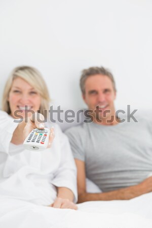 Stock photo: Smiling mature woman on the bed with reading husband behind her