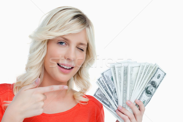 Woman winking an eye while pointing her finger on a fan of dollar bank notes Stock photo © wavebreak_media