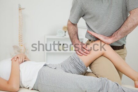 Serious doctor holding the leg of a woman in a room Stock photo © wavebreak_media