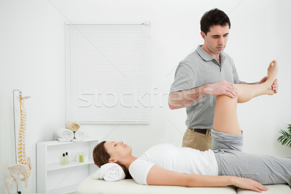 Doctor examining the leg of his patient while raising it in a medical room Stock photo © wavebreak_media