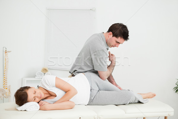 Chiropractor massaging the thigh of his patient while using his elbow in a room Stock photo © wavebreak_media