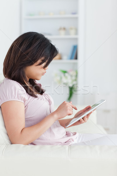 Woman holding a tablet while she sits on a sofa in a living room Stock photo © wavebreak_media