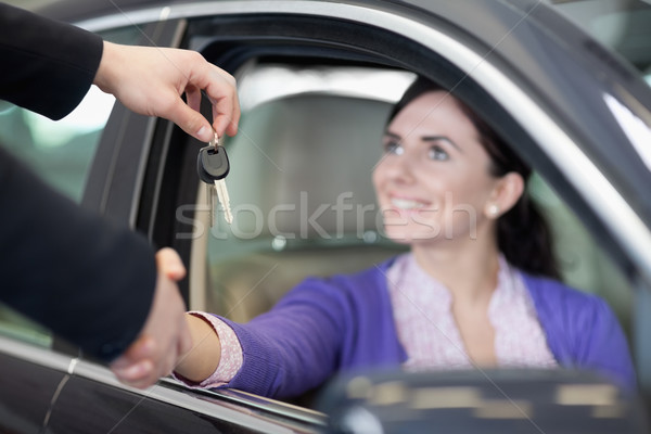 Woman in a car while shaking a hand and receiving car keys in a car dealership Stock photo © wavebreak_media