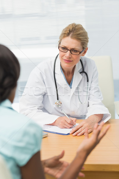 Concerned doctor listening to her patient and taking notes Stock photo © wavebreak_media