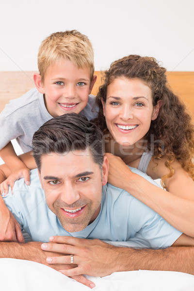 Attractive young family smiling at camera on bed posing Stock photo © wavebreak_media