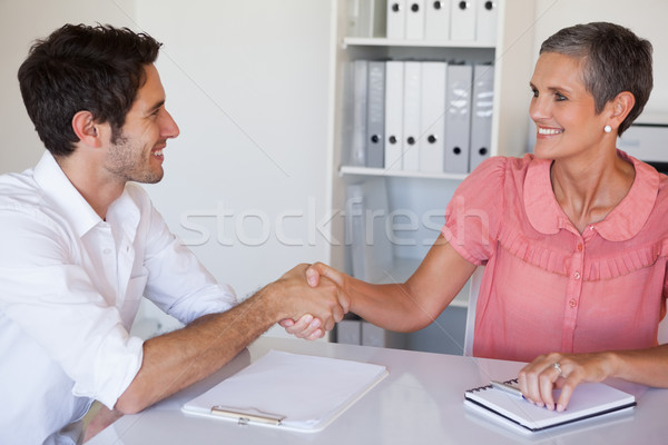 Casual business people shaking hands at desk and smiling Stock photo © wavebreak_media