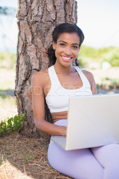 Potrivi femeie şedinţei copac folosind laptop Imagine de stoc © wavebreak_media