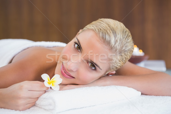 Stock photo: Woman holding flower on massage table at spa center