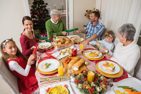 Smiling family pulling christmas crackers at the dinner table Stock photo © wavebreak_media