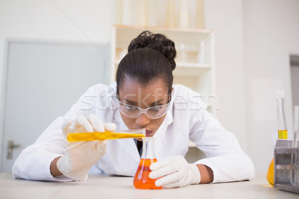 Concentrated scientist pouring orange fluid  Stock photo © wavebreak_media