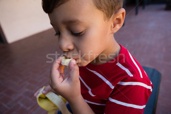 Close up of boy eating banana while sitting on chair Stock photo © wavebreak_media