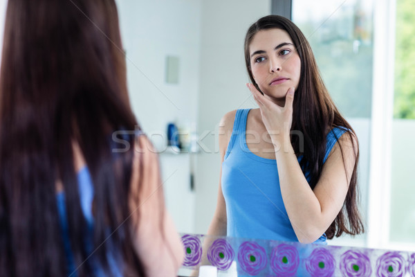 Unsmiling brunette looking her reflection in the mirror Stock photo © wavebreak_media
