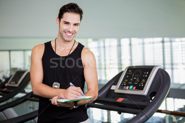 Smiling man on treadmill writing on clipboard Stock photo © wavebreak_media