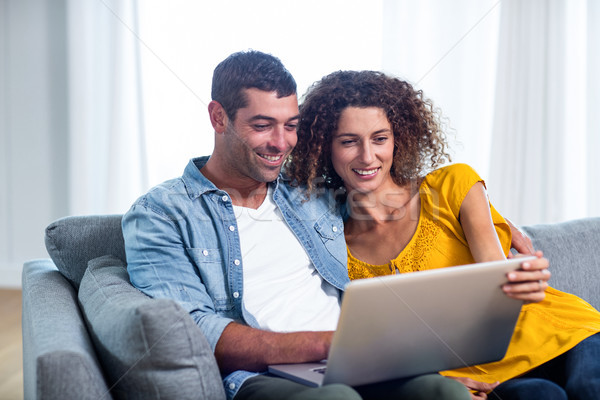 Stock photo: Young couple sitting on sofa and using laptop