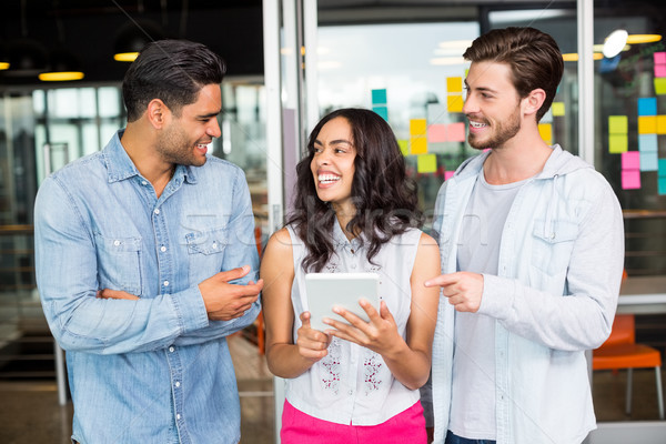 Three smiling executives discussing over digital tablet Stock photo © wavebreak_media