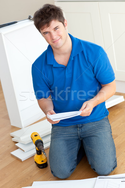 Charismatic young man reading the instructions to assemble furniture in the kitchen at home Stock photo © wavebreak_media
