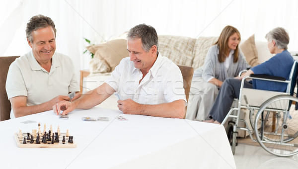 Stock photo: Men playing cards while their wifes are talking