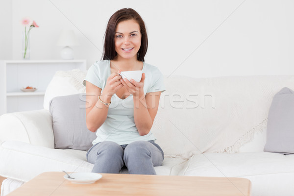 Stock photo: Smiling dark-haired woman drinking tea in her living room