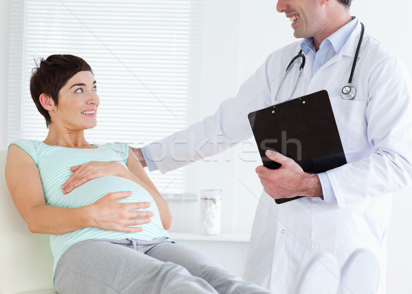 Stock photo: Pregnant woman lying down while talking to her doctor