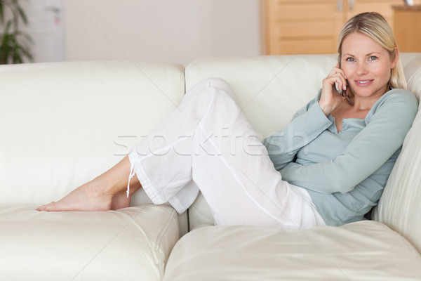微笑的女人 坐在 榻 聽 呼叫者 電話 商業照片 © wavebreak_media