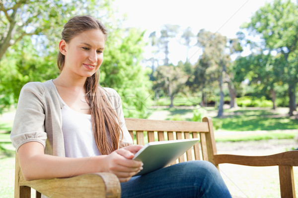 Smiling young woman using a tablet on a park bench Stock photo © wavebreak_media