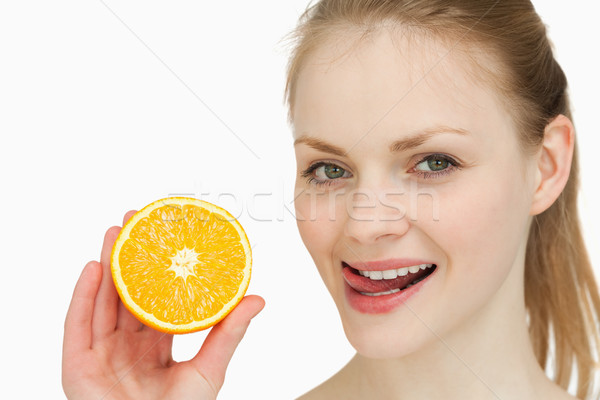 Woman holding an orange while placing her tongue on her lips against white background Stock photo © wavebreak_media