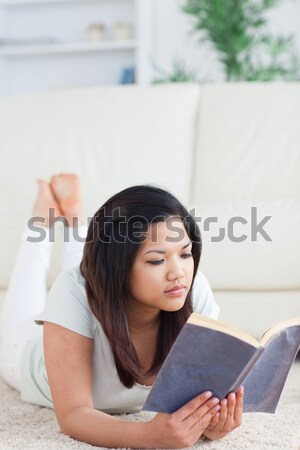 Stock photo: Woman lying on the floor reading a book in a living room