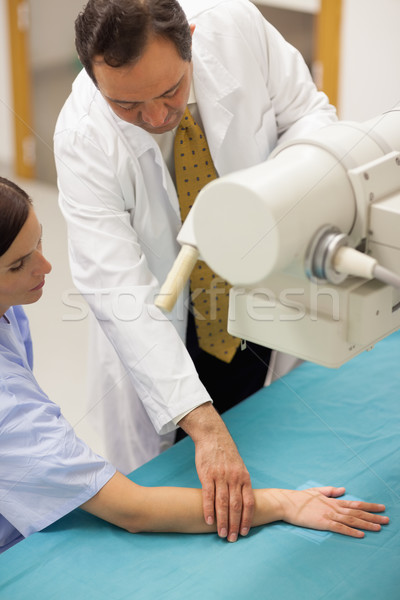 Doctor placing the arm of a patient on a table in a radiography room Stock photo © wavebreak_media