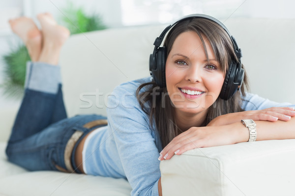 Stock photo: Woman listening music looking happy on sofa in the living room