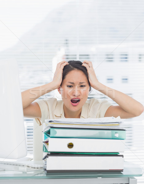 Angry businesswoman shouting with stack of folders at desk Stock photo © wavebreak_media