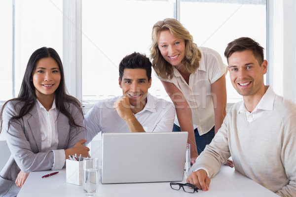 [[stock_photo]]: Souriant · équipe · commerciale · réunion · utilisant · un · ordinateur · portable · bureau