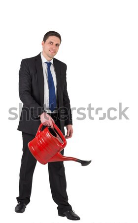 Businessman watering with red can and smiling at camera Stock photo © wavebreak_media