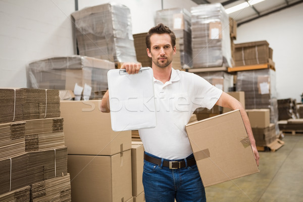 Delivery man with box and clipboard in warehouse Stock photo © wavebreak_media