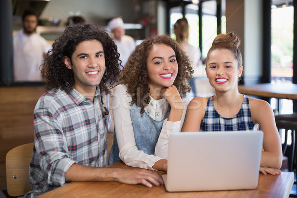 Smiling friends using laptop while sitting in restaurant Stock photo © wavebreak_media